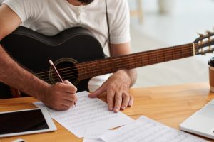 man songwriting with guitar